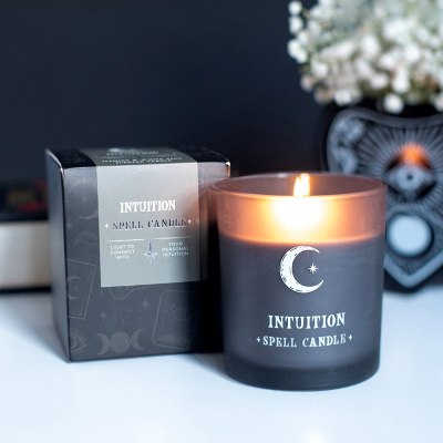 Vela acesa Intuition Spell Candle em vidro cinzento com caixa preta ao lado