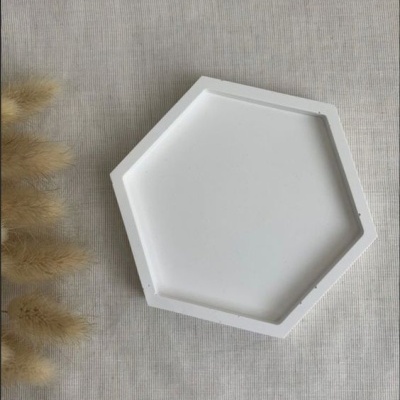 Tabuleiro branco hexagonal sobre fundo bege com planta decorativa
