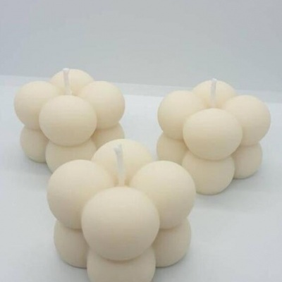Três velas creme em formato de cubo feitas de esferas