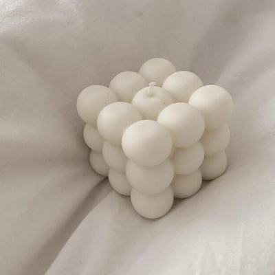 Vela cubo de esferas brancas sobre tecido branco