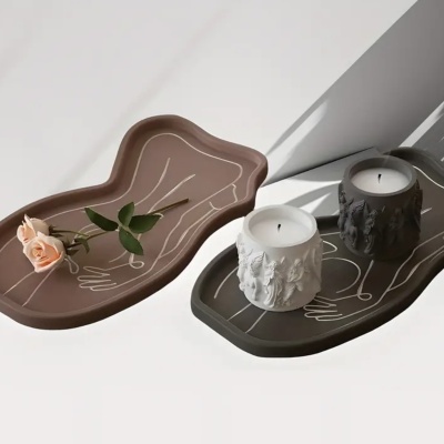 Dois tabuleiros decorativos com velas e uma rosa, com padrões abstratos lineares.