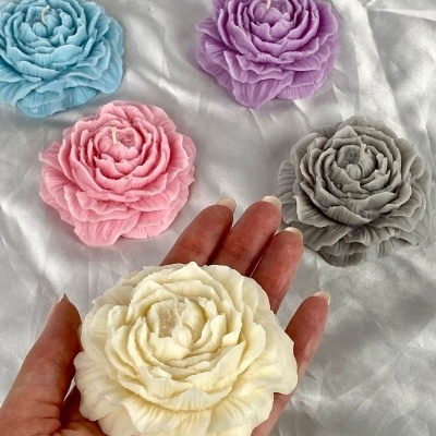 Velas em forma de flor em várias cores sobre tecido branco