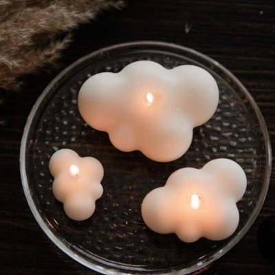 Três velas em forma de nuvem acesas sobre prato de vidro
