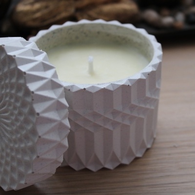 Vela branca em recipiente decorativo branco com padrão geométrico