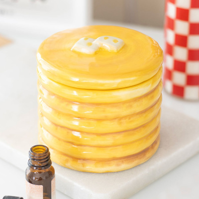 Pote cerâmico amarelo formato panquecas com acessório branco e amarelo no topo