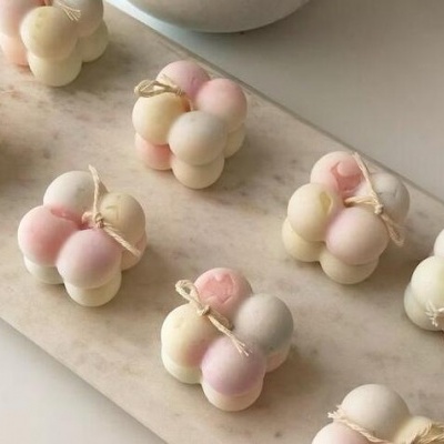 Velas decorativas em forma de cubo com bolas arredondadas e laço de corda em base de mármore