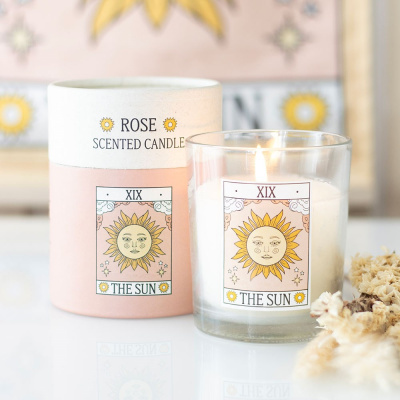 Vela aromática em copo de vidro com etiqueta sol e embalagem cilíndrica rosa e branca