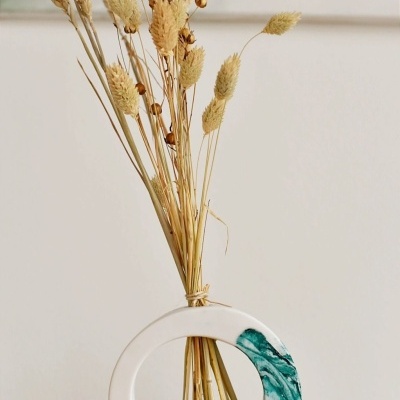 Vaso cerâmico circular branco com detalhes verdes e flores secas naturais