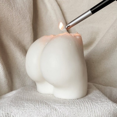 Vela branca em forma de partes traseiras humanas com maçarico a acender