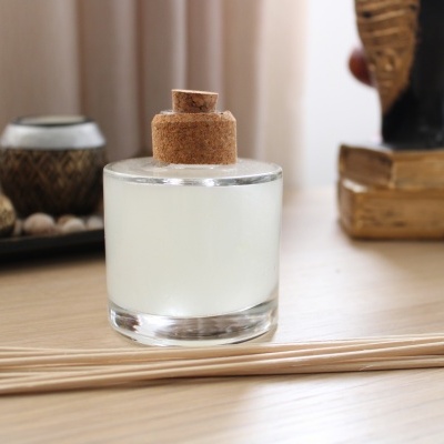 Frasco de vidro com líquido branco e rolha em superfície de madeira com decoração ao fundo