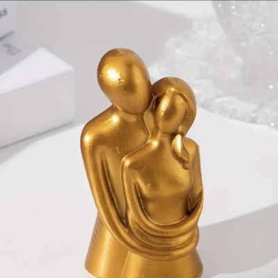 Figura decorativa dourada de duas pessoas abraçadas