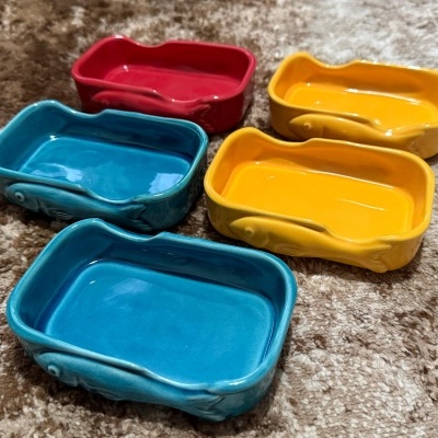 Mini travessas retangulares coloridas de cerâmica sobre tapete castanho.