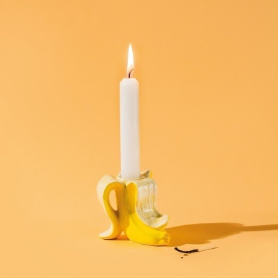 Suporte de vela em forma de banana com vela branca acesa