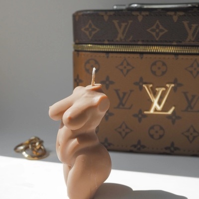 Vela corpo feminino pele, joias douradas e mala Louis Vuitton castanha