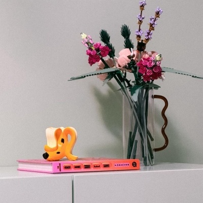 Vaso de vidro com flores artificiais e livros coloridos sobre móvel branco