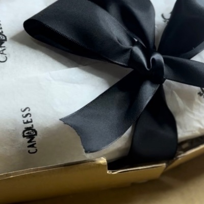 Caixa dourada com embalagem em papel branco e laço preto