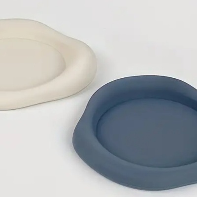 Dois pratos de cerâmica com bordas onduladas em azul escuro e bege claro.