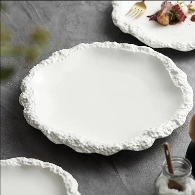 Prato branco com borda texturizada e comida ao fundo