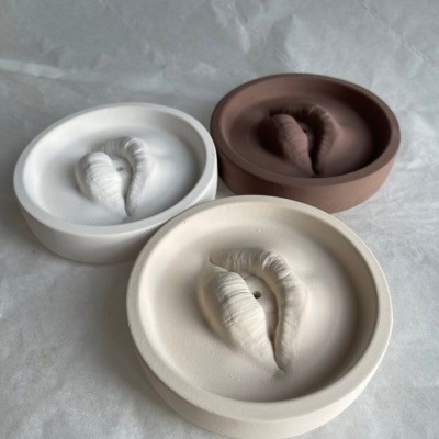 Três cinzeiros redondos de cerâmica em cores branco, castanho e bege com design interior orgânico