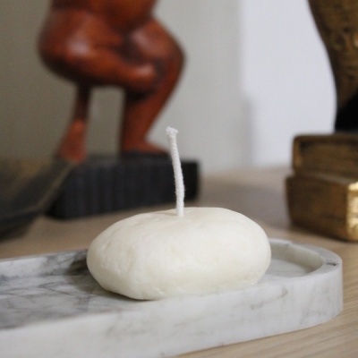 vela branca oval com pavio sobre prato de mármore