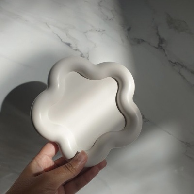 Prato decorativo branco ondulado em cerâmica segurado à mão
