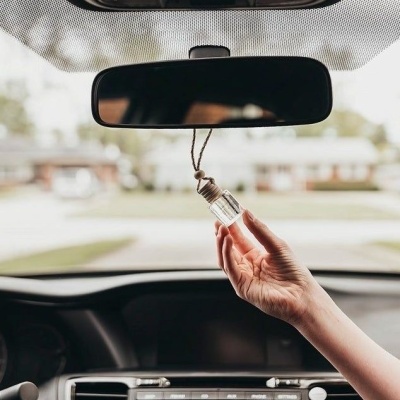 Frasco pendurado no espelho retrovisor do carro com mão segurando
