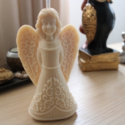 Estatueta de anjo branca com padrão floral, superfície de madeira clara.