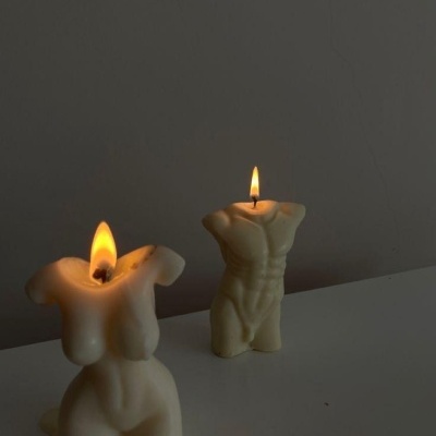 Velas acesas em forma de torso humano feminino e masculino sobre mesa branca