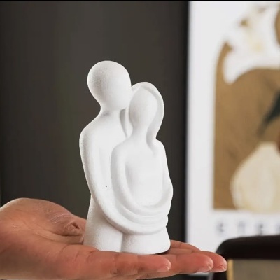 Escultura branca minimalista de casal em cerâmica ou gesso, acabamento fosco, em mão humana