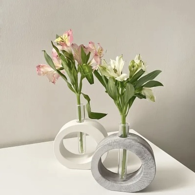 Duas flores em vasos de vidro dentro de suportes circulares branco e cinzento