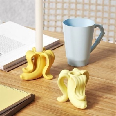 Castiçal, suporte e caneca em mesa de madeira clara