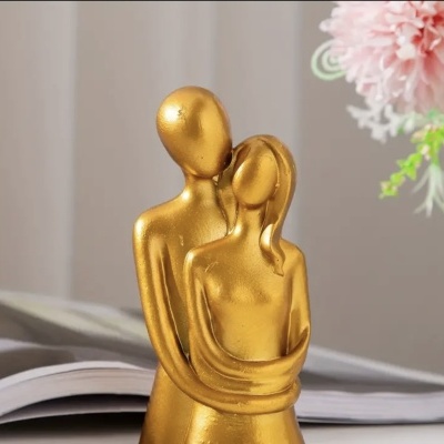 Escultura dourada abstrata de casal abraçado