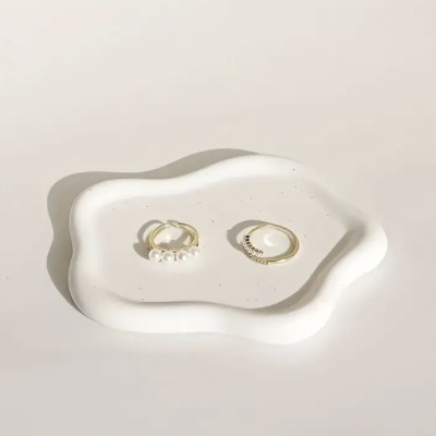 Dois anéis dourados em prato decorativo branco irregular sobre fundo branco