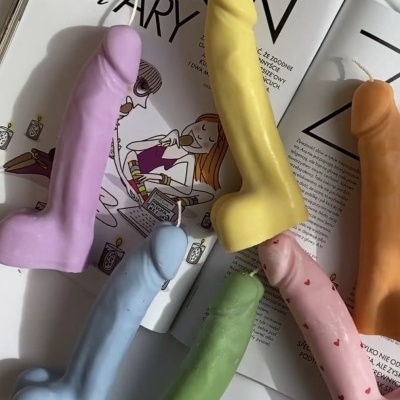 Velas coloridas em formato fálico sobre revista aberta