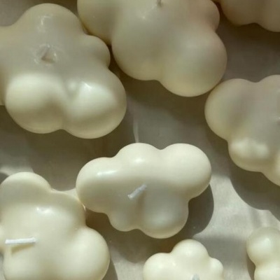 Velas brancas em forma de nuvem de cera com pavios na superfície clara