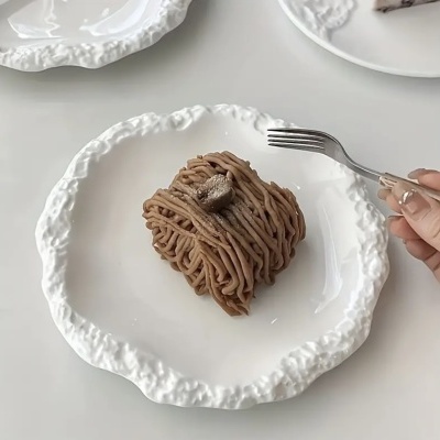 Sobremesa castanha num prato branco com design ondulado e garfo à direita