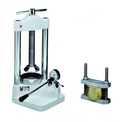 Prensa laboratorial branca e cromada com manivela e medidor manométrico, ao lado de dispositivo com parafusos verticais e peça amarela.