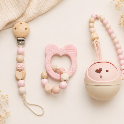 Acessórios para bebé em tons rosa pastel e bege sobre fundo neutro