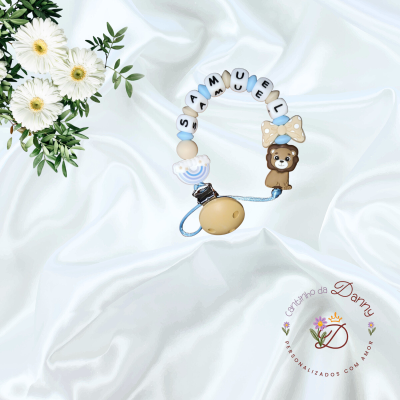 Prendedor de chucha com nome SAMUEL, leão, laço e arco-íris em fundo branco com flores