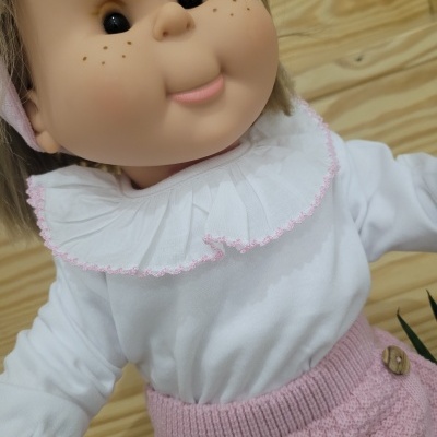 Boneca com roupa branca e rosa em fundo de madeira clara