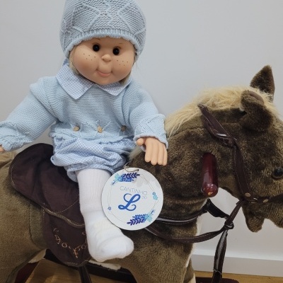 Boneco de bebê azul em cavalo de peluche castanho com cabresto