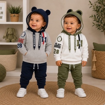 Dois bebés com fatos de treino com capuz com orelhas, um cinzento e azul, outro branco e verde, em cenário interior decorado.