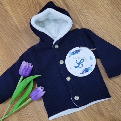 Casaco azul escuro com forro branco e botões, flores roxas ao lado