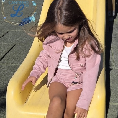 Menina sentada no final de um escorrega amarelo no parque