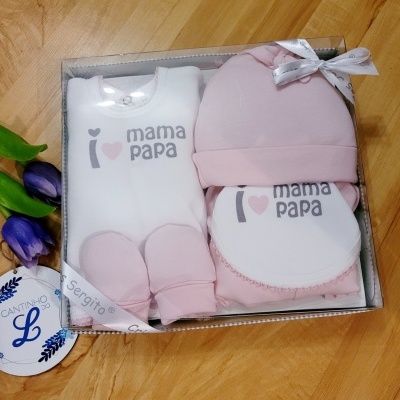 Conjunto de roupinha de bebé branco e rosa claro com texto 'I ♥ mama papa' numa caixa transparente com laço