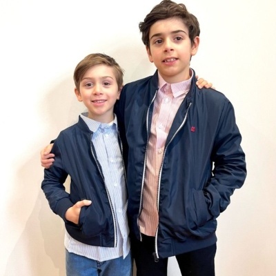 Dois rapazes com casacos azuis escuros e camisas, em fundo branco