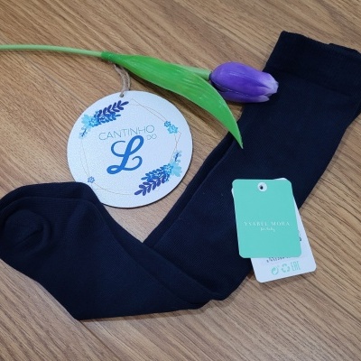 Meias azuis escuras com etiquetas sobre madeira clara e tulipa roxa