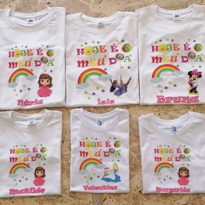Seis t-shirts brancas infantis com texto colorido e desenhos de personagens e arco-íris