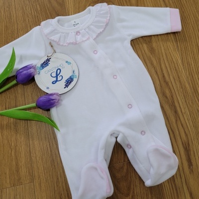 Macacão branco de bebé com detalhes rosa e etiqueta decorativa pendurada