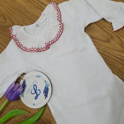 Body de bebé branco com gola bordada vermelha e flores roxas ao lado